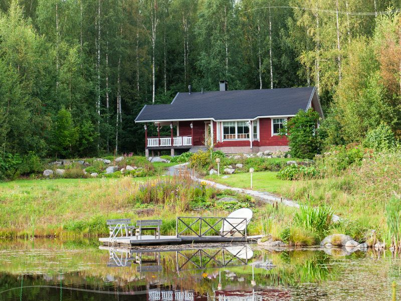 Punainen kesämökki ja järven ranta